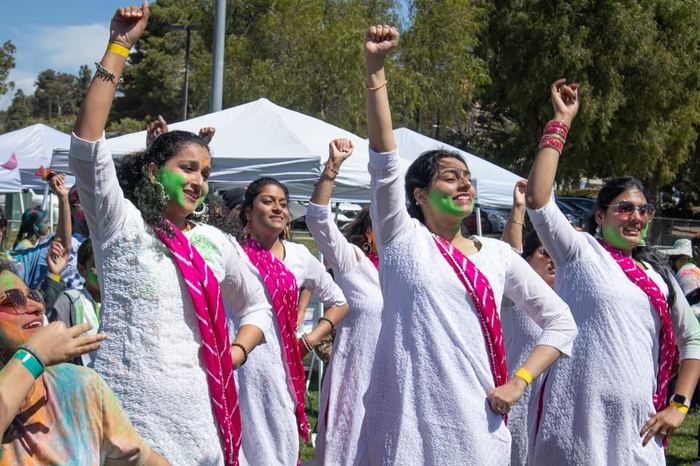 Dancers celebrating Holi in white outfits with color powder